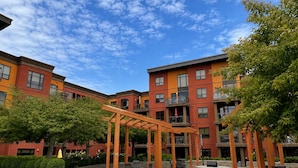 Ein Innenhof mit Außenbestuhlung, einer Pergola und mehrstöckigen Gebäuden mit Balkonen.