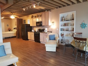 Un espace de vie compact comprenant un coin cuisine, un coin repas avec une chaise et une table, un canapé et un lit.