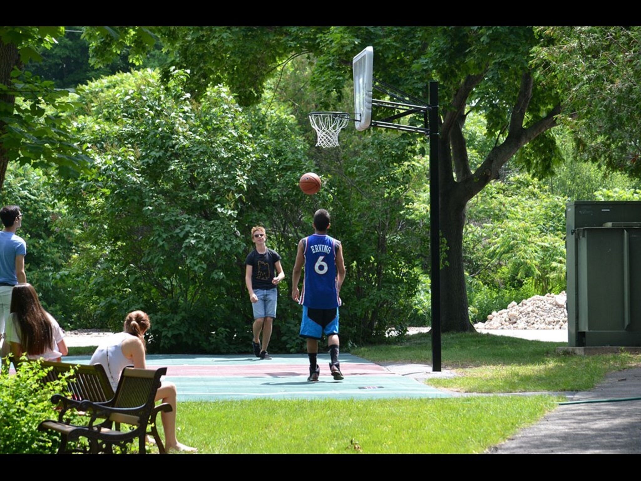 Ein Basketballplatz im Freien, umgeben von Bäumen.