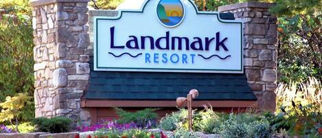 A sign for Landmark Resort with a stone structure and colorful landscaping.