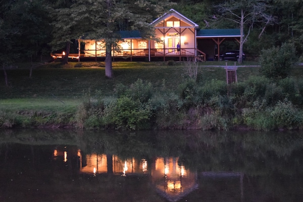 The cabin reflects in the New River as night settles in.