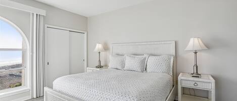 Una camera da letto con un letto grande, due comodini con lampade, un armadio e vista sull'esterno attraverso una grande finestra.
