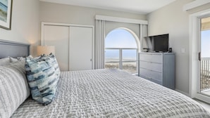 A bedroom with a bed, a dresser, a television, and a view of the beach. - Modern 5th Floor Villa w/ Panoramic Views (Hilton Head Island)