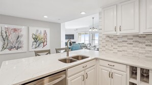 A modern kitchen with white cabinetry, a marble countertop, and a brick backsplash. - Modern 5th Floor Villa w/ Panoramic Views (Hilton Head Island)
