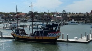 Un barco grande de varios pisos atracado en un puerto deportivo, con vista despejada a los edificios y al agua circundantes.