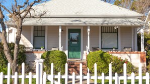 A two-story house with a green door, white picket fence, and a brick foundation. - Two Master-King Suites+! (Sonoma)