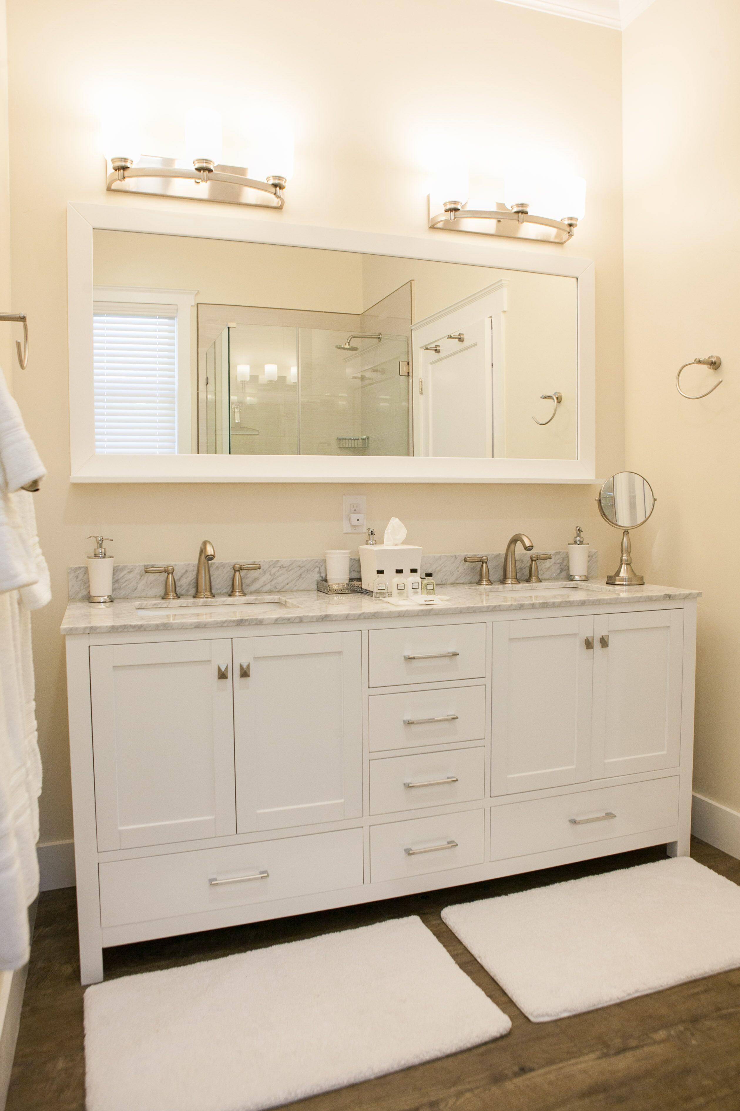 A bathroom with a large mirror, two sinks, and a vanity with drawers.