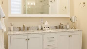 A bathroom with a large mirror, two sinks, and a vanity with drawers.