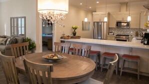 A modern kitchen with a central island, stainless steel appliances, and wooden chairs. - Two Master-King Suites+! (Sonoma)