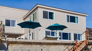 Ein zweistöckiges Gebäude mit Balkon, Treppe und zwei Sonnenschirmen.