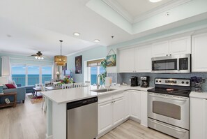 A modern kitchen with white cabinetry, a dishwasher, a stove, and a microwave.