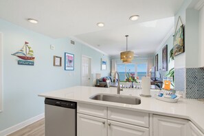 A kitchen with a central island, a dishwasher, and a view to the dining area.