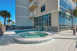 Un edificio moderno con piscina, mobiliario exterior y vistas a palmeras.