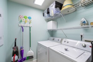 A laundry room with a washing machine, dryer, and ironing station.