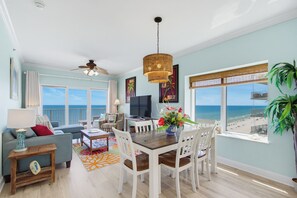 Un amplio salón con mesa de comedor, sillas y vistas a la playa.