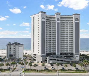 Un hotel de varios pisos con patio central, garaje de estacionamiento y vista al mar.