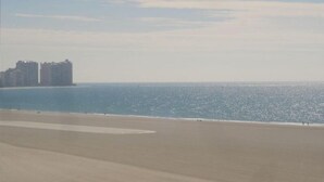 A beach with a clear view of the ocean and distant buildings.