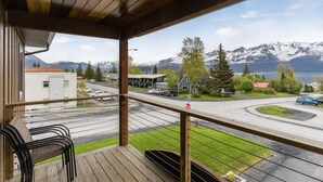 En träveranda med utsikt över en väg, ett stoppskylt och ett bergigt landskap.