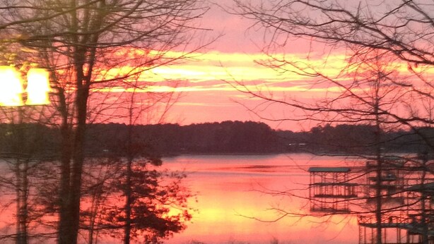 A sunset over a body of water with trees in the foreground. - Beautiful Lakefront Getaway (Cedar Bluff)