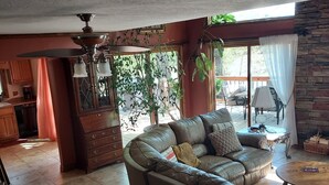 A spacious living room with a leather sofa, a dining area, and a kitchen in the background. - Beautiful Lakefront Getaway (Cedar Bluff)