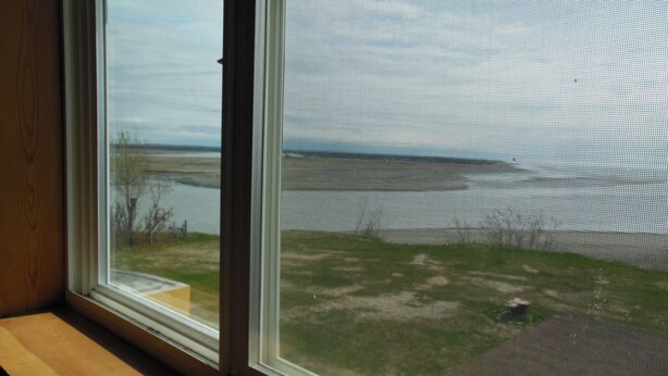 A room with a large window overlooking a grassy area and a body of water.