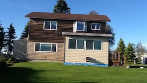 A two-story wooden house with a front porch and a small attached garage.