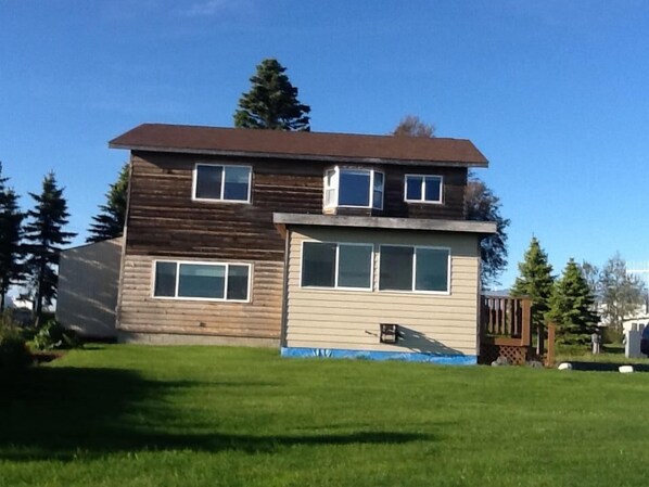 A two-story wooden house with a front porch and a small attached garage.