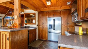 Una cocina con armarios de madera, un refrigerador de acero inoxidable y una encimera de granito.