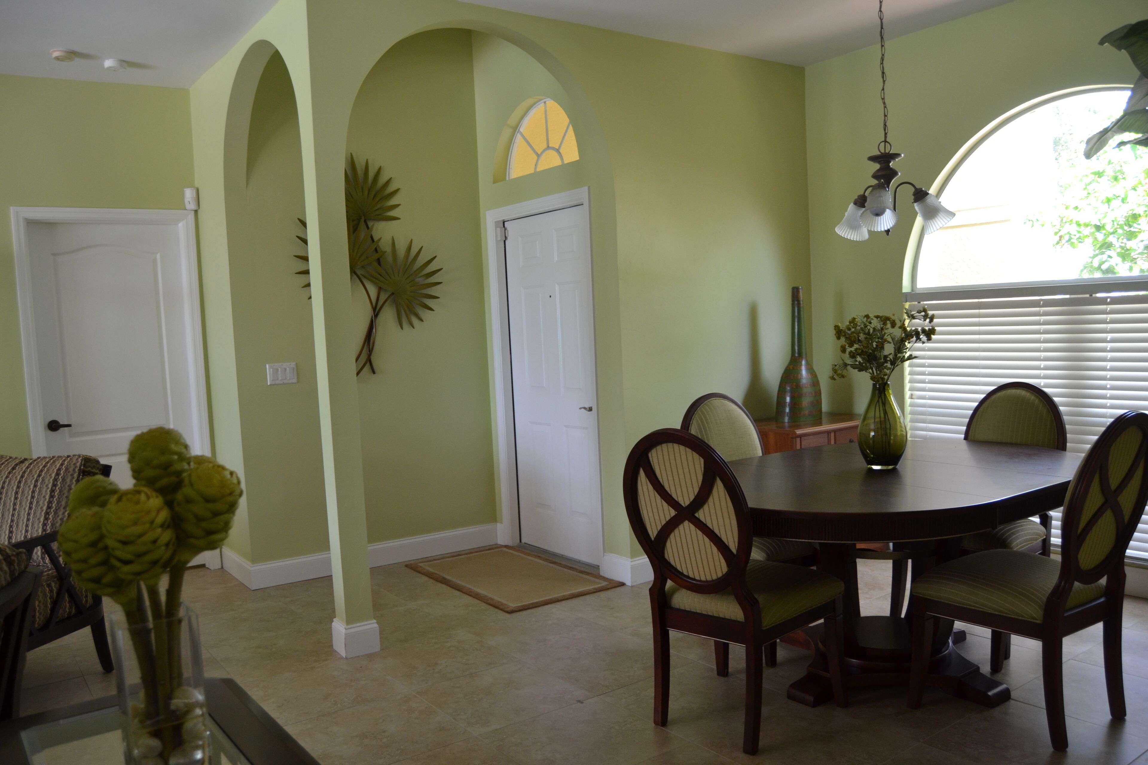 A dining area with a round table, chairs, and a vase of flowers.