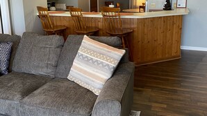 Una sala de estar con un sofá gris, una mesa de comedor de madera y sillas.