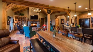 A spacious living room with a large wooden dining table, comfortable seating, and a fireplace.