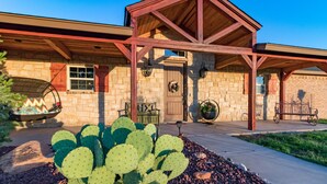 A stone building with a wooden porch, a cactus garden, and outdoor seating.