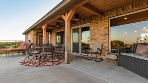 An outdoor patio area with a brick wall, wooden beams, and a glass door leading to a covered space.