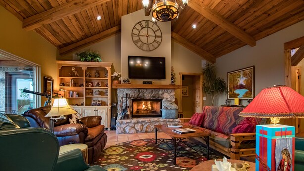 A cozy living room with a fireplace, leather furniture, and a mounted clock.