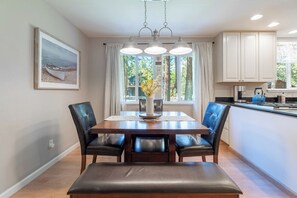 Un coin repas avec une table en bois et quatre chaises, un vase rempli de fleurs et un tableau accroché au mur.