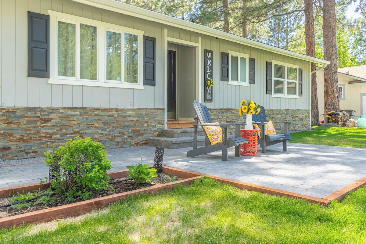 A house with a stone foundation, a porch with a bench and a table, and a welcome sign.