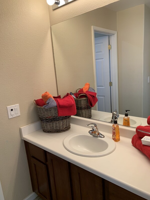 A bathroom with a white sink, a mirror, and wicker baskets with towels.