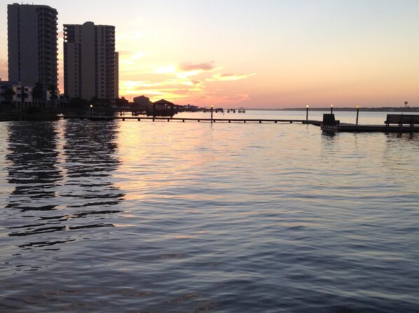 A waterfront view with a pier extending into calm water, surrounded by high-rise buildings.