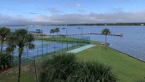 Un campo da tennis con vista sull'acqua e un molo.