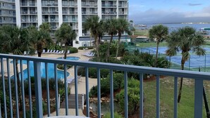 Un hotel con diversi piani, piscina all'aperto, palme e vista sull'oceano.