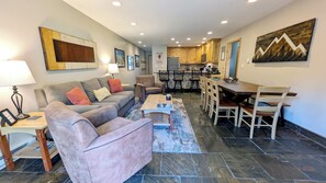 A living room with a sofa, armchairs, a coffee table, and a dining area with a wooden table and chairs. - Luxury Condo w/ FREE WiFi, Parking, Heated Pool, Hot Tubs, Skier Shuttles (Avon)