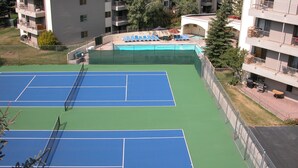 Una cancha de tenis rodeada de edificios de apartamentos con balcones.