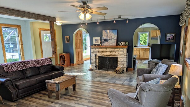 Una sala de estar con chimenea, sofá de cuero, sillón y mesa de centro de madera.