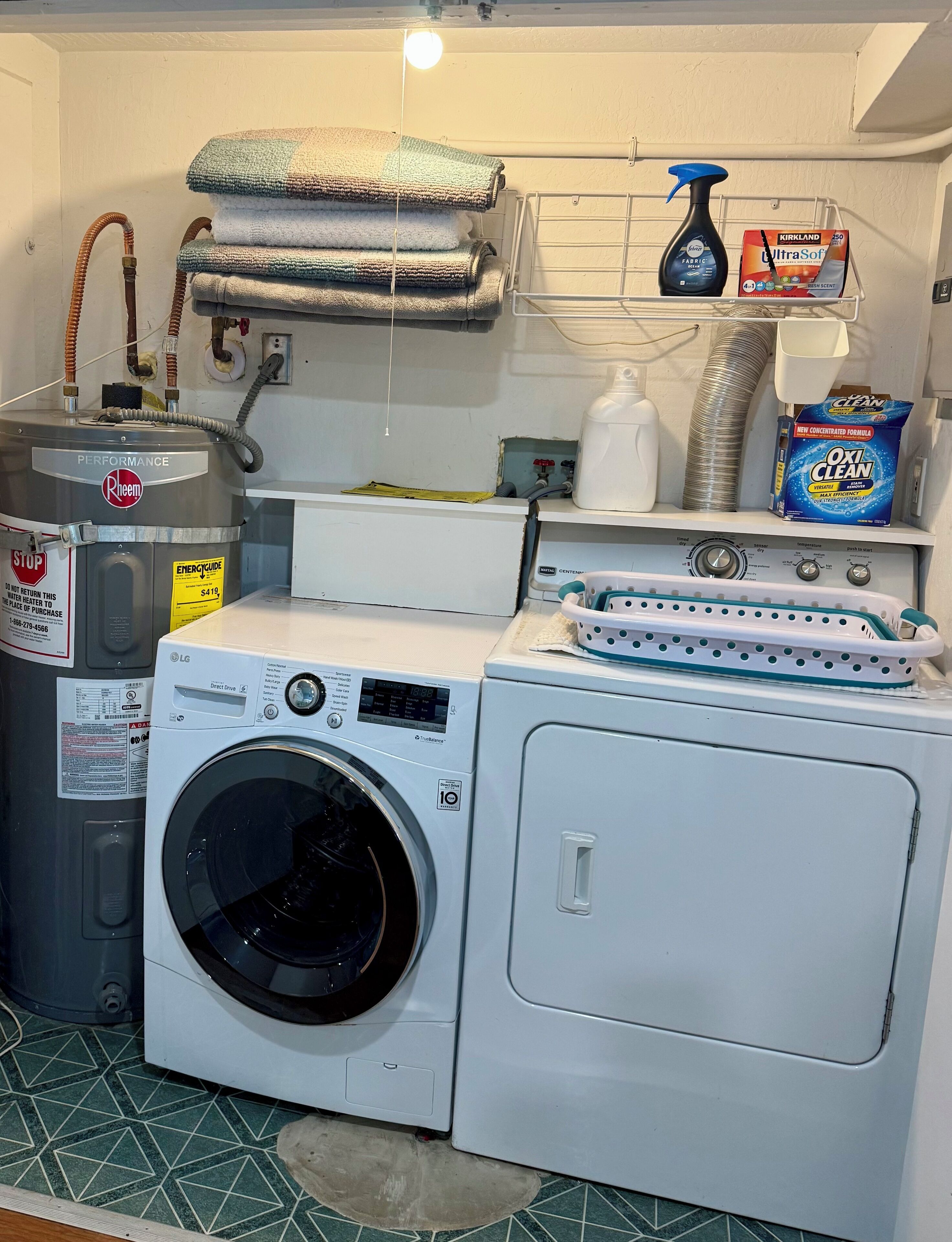 Un espace buanderie équipé d’un lave-linge et d’un sèche-linge à chargement frontal, d’un étendoir empilable et de divers produits de nettoyage.