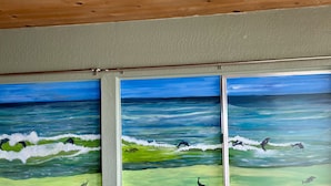 Ein Zimmer mit einem großen Gemälde von Delfinen und Wellen an der Wand.