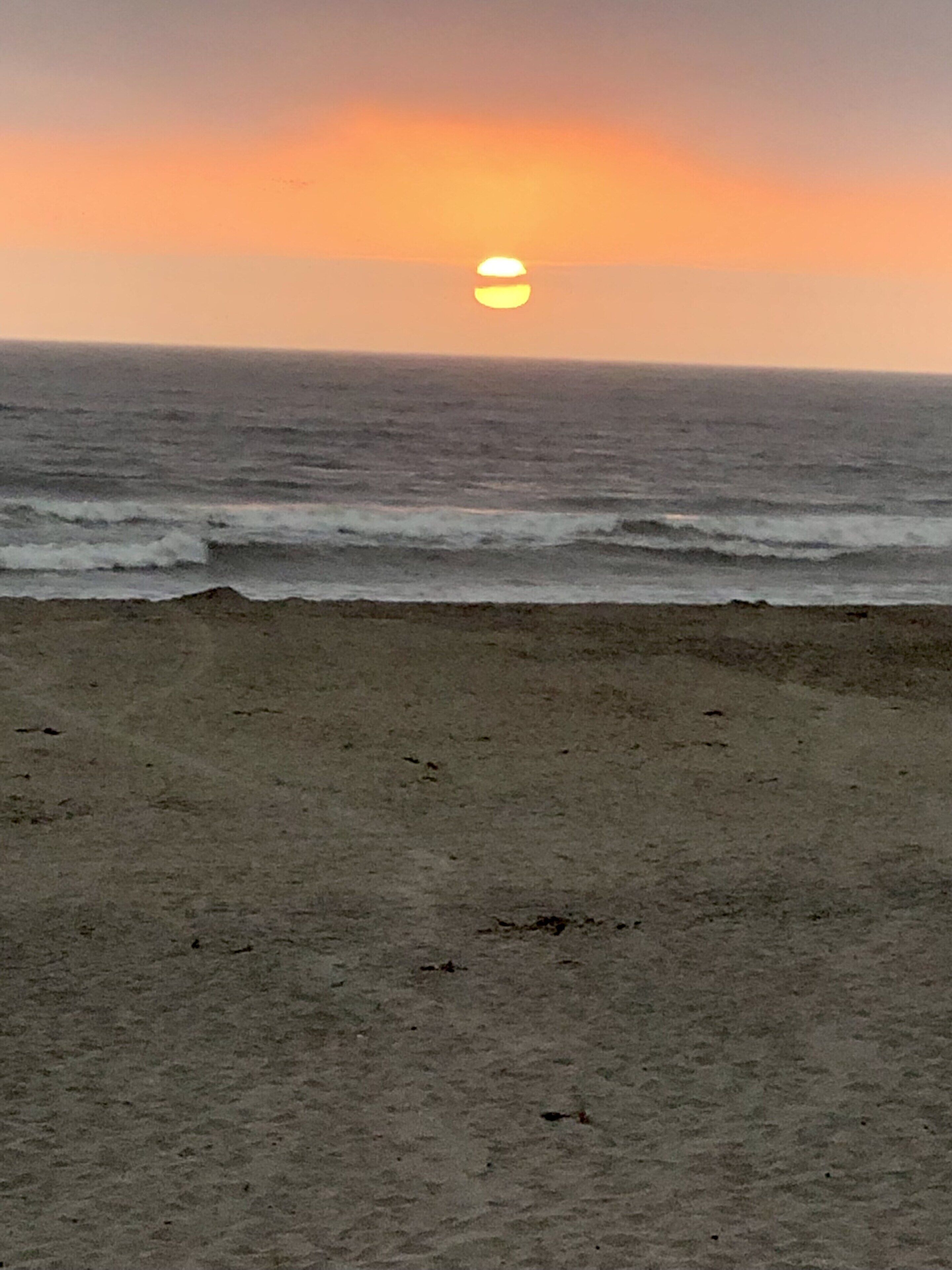 Een strand met een zonsondergang boven de oceaan.
