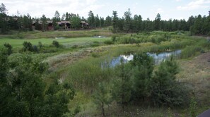 A golf course with a pond, surrounded by dense forest and a few buildings in the background. - Stunning cabin in Torreon with unbeatable views—your search ends here! (Show Low)