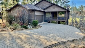 A two-story house with a stone facade, a covered porch, and a driveway leading to a garage. - Stunning cabin in Torreon with unbeatable views—your search ends here! (Show Low)