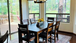 A dining area with a table, chairs, a chandelier, and a view through large windows. - Stunning cabin in Torreon with unbeatable views—your search ends here! (Show Low)