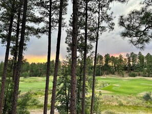A golf course surrounded by tall pine trees with a sunset in the background. - Stunning cabin in Torreon with unbeatable views—your search ends here! (Show Low)